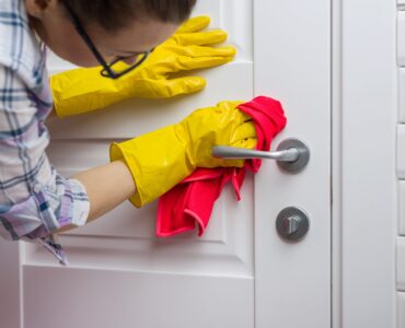 Professional cleaning service. Woman housekeeper wipes the door with rag.