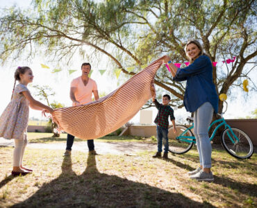 Happy family placing picnic blanket in the park on a sunny day