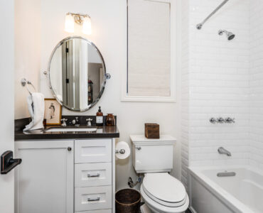 Modern bathroom with white tub, toilet, sink, and mirror